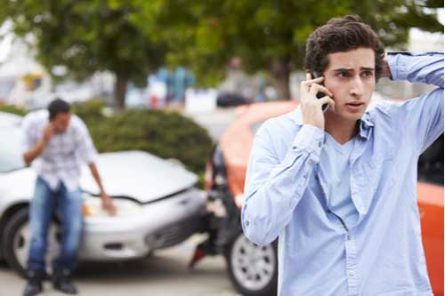 Young male driver on phone after crash, Riverdale car accident lawyer concept