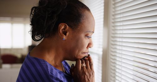Mourning older woman looking out window concept of South Fulton wrongful death lawyer