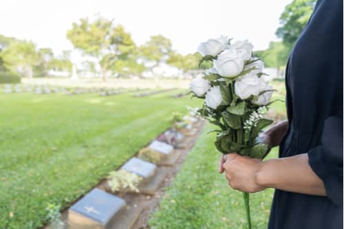 Woman with white roses at grave, Riverdale wrongful death lawyer concept